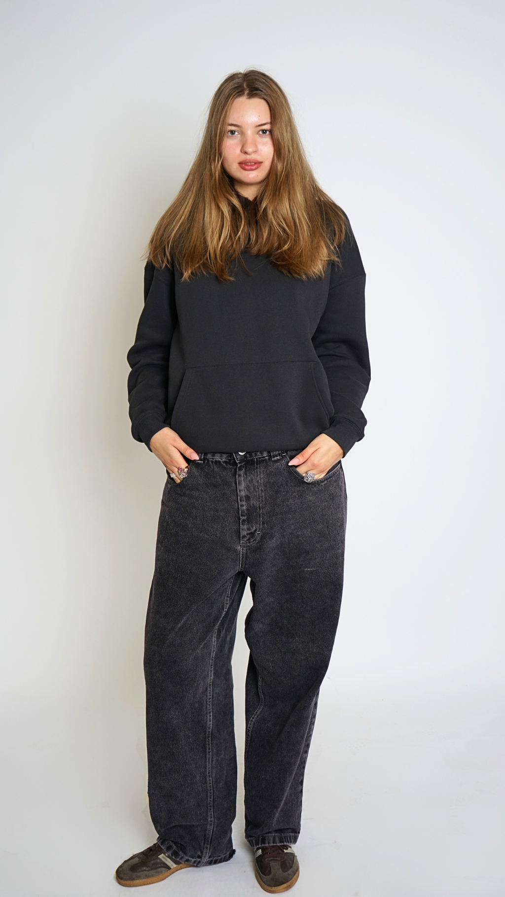 Person wearing a black sweater and dark jeans against a white background