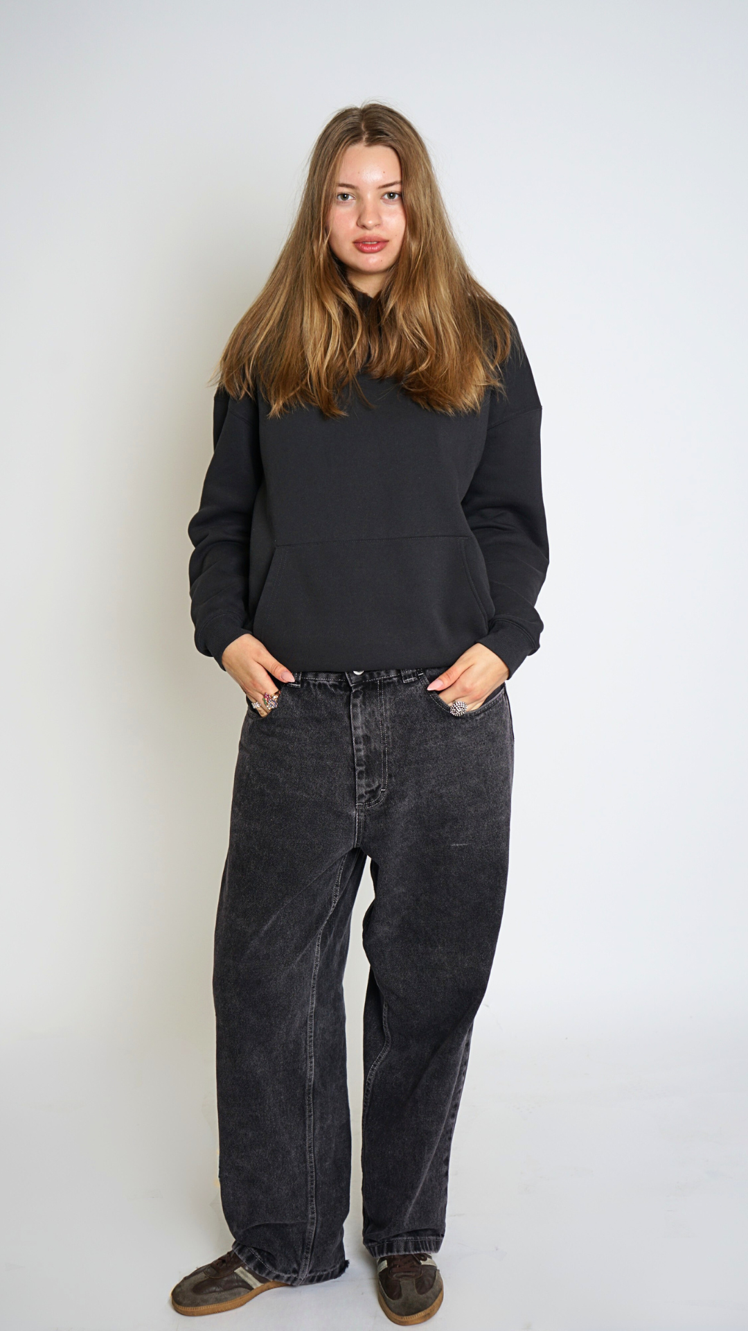 Person wearing a black sweater and dark jeans against a white background