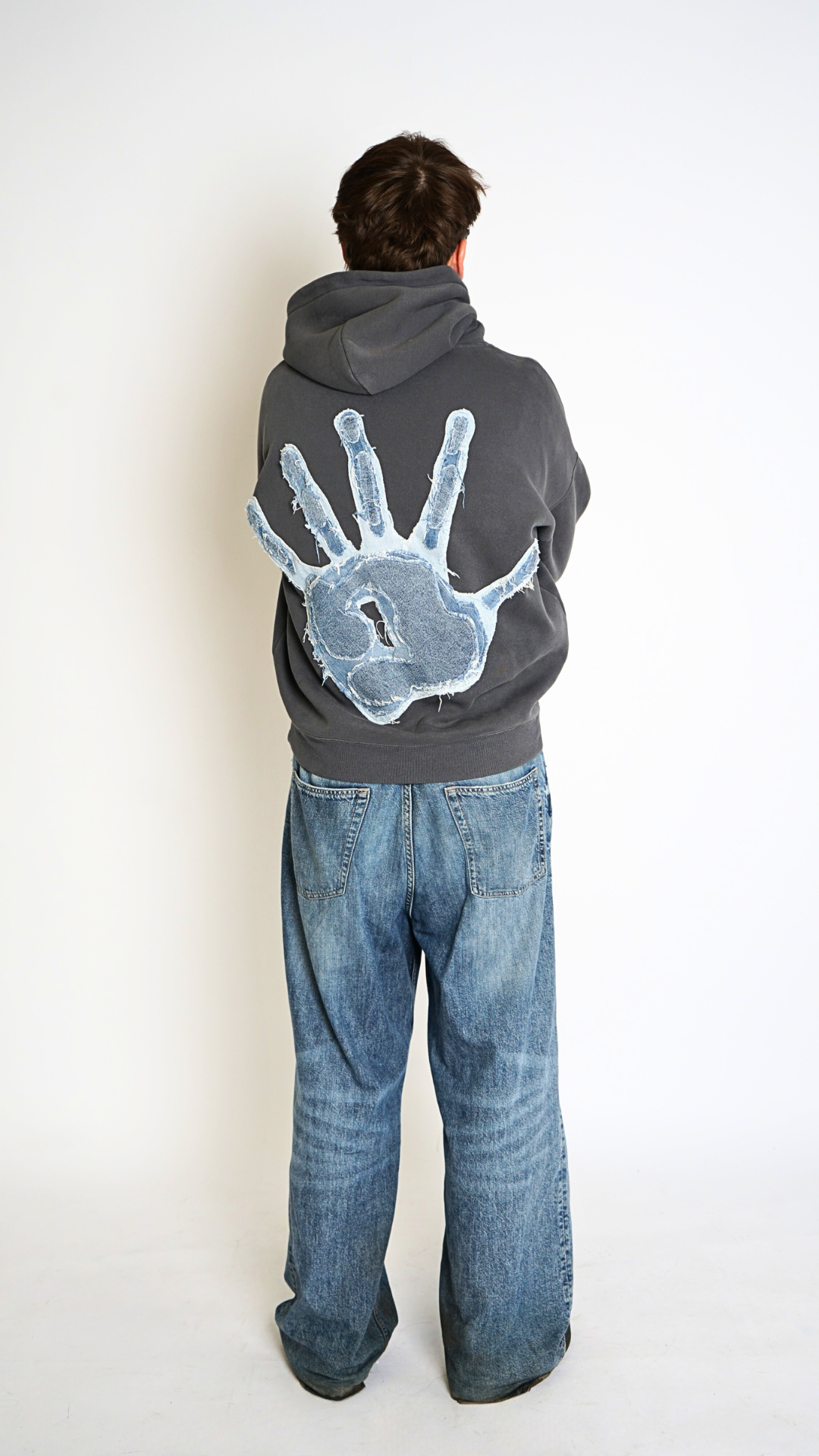 Person wearing a hoodie with a handprint design on the back, standing against a white background