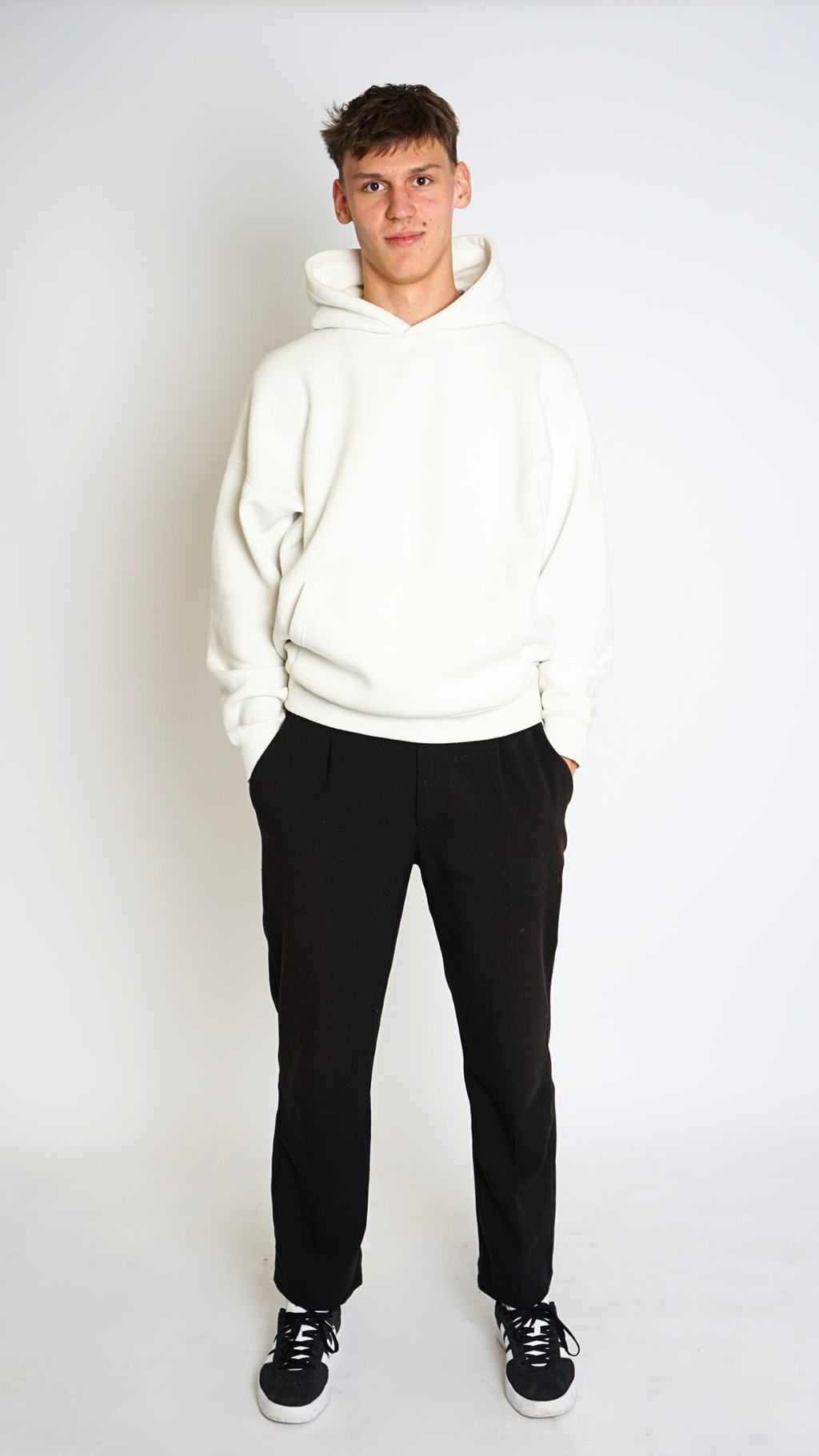 Person wearing a white hoodie and black pants on a white background