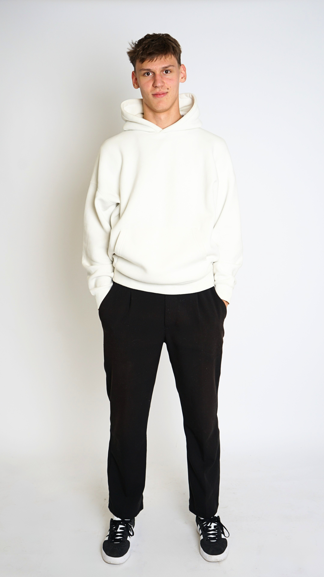 Person wearing a white hoodie and black pants on a white background